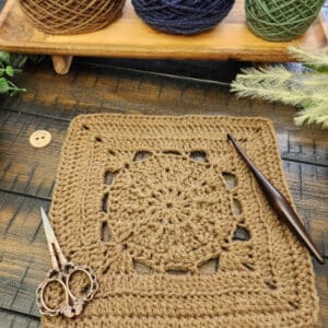Flat lay of the Hype Square crochet pattern styled with scissors and wooden crochet hook, part of the Riverwood Square CAL.